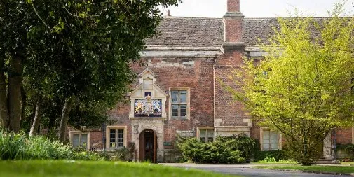 Image of the University of York building with a lawn and trees in the foreground. 